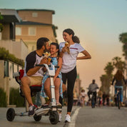 Family eating ice cream around the Moving Life ATTO Sport scooter at sunset.