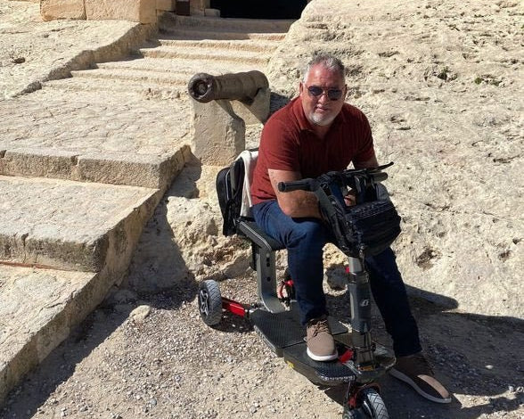 ATTO folding mobility scooter parked outdoors on a rural path, showcasing its compact design